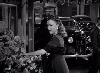 Movie still from “The Leopard Man” (1943), directed by Jacques Tourneur – A black and white photo of a woman in a black dress; Medium shot, Over the shoulder angle
