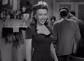 Movie still from “The Leopard Man” (1943), directed by Jacques Tourneur – An old photo of a woman smiling for the camera; Medium shot, Low angle