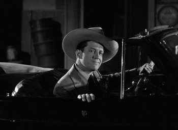 Movie still from “The Leopard Man” (1943), directed by Jacques Tourneur – A black and white photo of a man wearing a cowboy hat; Medium shot, Low angle