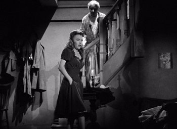 Movie still from “The Leopard Man” (1943), directed by Jacques Tourneur – An older man and a young woman standing on a staircase; Medium shot, High angle