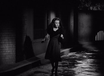 Movie still from “The Leopard Man” (1943), directed by Jacques Tourneur – A woman in a black dress walking down a street; Medium shot, High angle