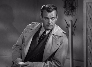 Movie still from “The Leopard Man” (1943), directed by Jacques Tourneur – A man in a trench coat and tie; Medium shot, Over the shoulder angle