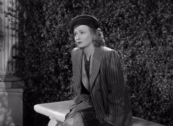 Movie still from “The Leopard Man” (1943), directed by Jacques Tourneur – A woman sitting on top of a bench wearing a hat; Medium shot, High angle