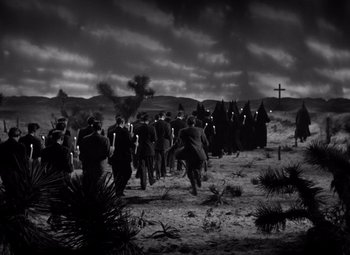 Movie still from “The Leopard Man” (1943), directed by Jacques Tourneur – A black and white photo of a group of people walking through the desert; Extreme Wide shot, High angle