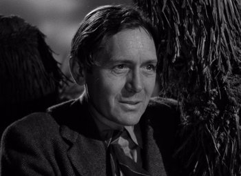 Movie still from “The Leopard Man” (1943), directed by Jacques Tourneur – A man in a suit and tie sitting in front of a tree; Close Up shot, Low angle