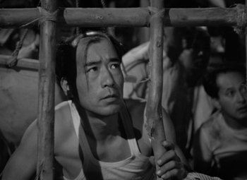 Movie still from “The Letter” (1940), directed by William Wyler – Black and white photograph of a man looking over a fence; Close Up shot, High angle