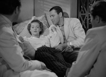 Movie still from “The Letter” (1940), directed by William Wyler – A man and a woman sitting on a bed with candles; Medium shot, High angle