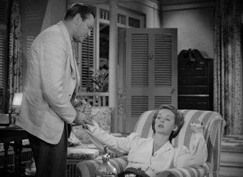 Movie still from “The Letter” (1940), directed by William Wyler – A man and a woman sitting in a chair; Medium shot, High angle