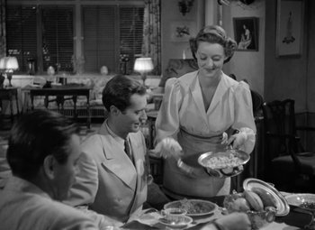 Movie still from “The Letter” (1940), directed by William Wyler – An old photo of a woman holding a plate of food; Medium shot, High angle