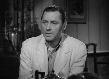 Movie still from “The Letter” (1940), directed by William Wyler – A man sitting at a table with a pipe in his mouth; Close Up shot, Over the shoulder angle