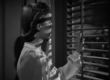 Movie still from “The Letter” (1940), directed by William Wyler – A black - and - white photo of a woman looking out a window; Close Up shot, Low angle