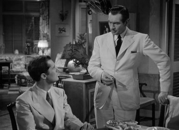 Movie still from “The Letter” (1940), directed by William Wyler – Two men in suits talking to each other in a room; Medium shot, Over the shoulder angle