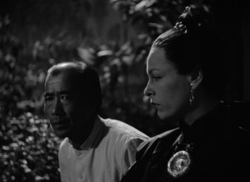 Movie still from “The Letter” (1940), directed by William Wyler – A man and a woman standing next to each other; Close Up shot, High angle