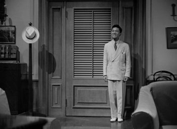 Movie still from “The Letter” (1940), directed by William Wyler – A black and white photo of a man standing in front of a door; Wide shot, High angle