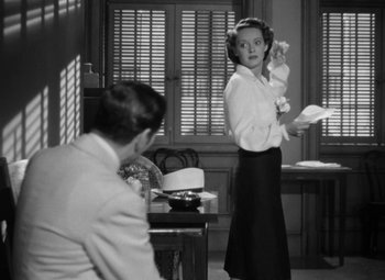 Movie still from “The Letter” (1940), directed by William Wyler – A woman standing in front of a man in front of a desk; Medium shot, High angle