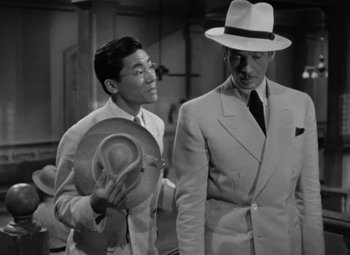 Movie still from “The Letter” (1940), directed by William Wyler – A man in a suit and a man in a hat; Medium shot, High angle