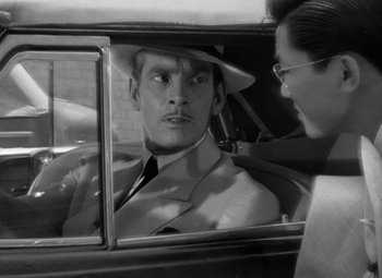 Movie still from “The Letter” (1940), directed by William Wyler – A black and white photo of a man in a hat in the back of a car; Close Up shot, Over the shoulder angle