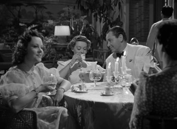 Movie still from “The Letter” (1940), directed by William Wyler – A black and white photo of people sitting at a table drinking wine; Medium shot, High angle