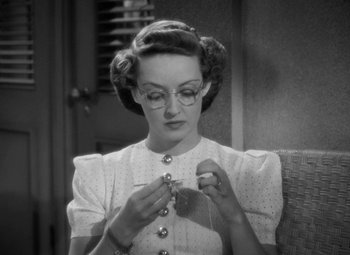 Movie still from “The Letter” (1940), directed by William Wyler – An old photo of a woman in a white dress knitting; Close Up shot, High angle