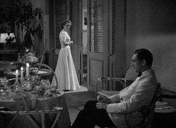 Movie still from “The Letter” (1940), directed by William Wyler – A man and a woman standing in front of a table; Wide shot, High angle