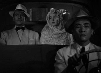 Movie still from “The Letter” (1940), directed by William Wyler – Two men and a woman sitting in the back of a car; Medium shot, High angle