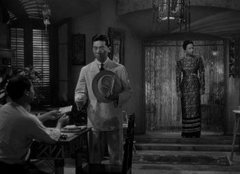 Movie still from “The Letter” (1940), directed by William Wyler – A man and a woman are standing at a table; Wide shot, Over the shoulder angle