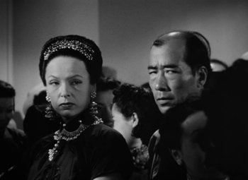 Movie still from “The Letter” (1940), directed by William Wyler – A man and a woman standing next to each other; Close Up shot, Over the shoulder angle