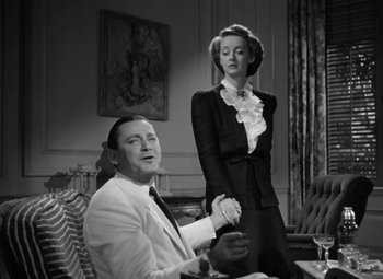 Movie still from “The Letter” (1940), directed by William Wyler – A man and a woman holding hands in a room; Medium shot, Low angle