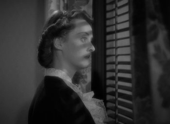 Movie still from “The Letter” (1940), directed by William Wyler – A black - and - white photo of a woman looking out of a window; Close Up shot, High angle