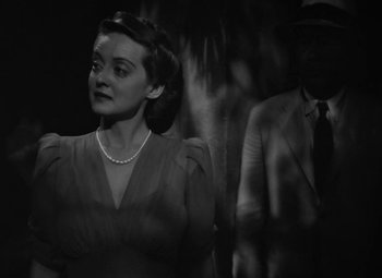 Movie still from “The Letter” (1940), directed by William Wyler – A woman standing next to a man wearing a suit and tie; Close Up shot, Low angle