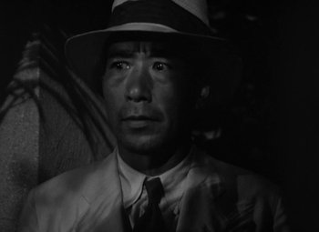 Movie still from “The Letter” (1940), directed by William Wyler – A black and white photo of a man wearing a hat; Close Up shot, Low angle