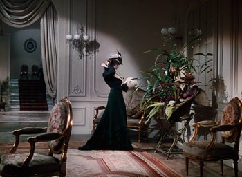 Movie still from “The Life and Death of Colonel Blimp” (1943), directed by Emeric Pressburger – A woman in a long green dress standing next to a plant; Wide shot, Low angle