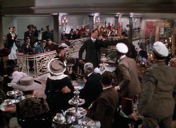 Movie still from “The Life and Death of Colonel Blimp” (1943), directed by Emeric Pressburger – A group of people sitting at tables in a room; Wide shot, High angle