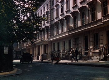 Movie still from “The Life and Death of Colonel Blimp” (1943), directed by Emeric Pressburger – A street scene with a person riding a horse drawn carriage on the sidewalk; Extreme Wide shot, High angle