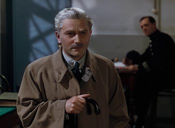 Movie still from “The Life and Death of Colonel Blimp” (1943), directed by Emeric Pressburger – An older man in a trench coat holding a cane; Medium shot, Over the shoulder angle