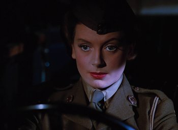 Movie still from “The Life and Death of Colonel Blimp” (1943), directed by Emeric Pressburger – A woman in a military uniform sitting behind a steering wheel; Close Up shot, Over the shoulder angle