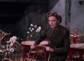 Movie still from “The Life and Death of Colonel Blimp” (1943), directed by Emeric Pressburger – A woman in a military uniform standing in front of red chairs; Medium shot, Low angle