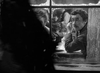 Movie still from “The Life of Emile Zola” (1937), directed by William Dieterle – A man sitting in front of a window while holding a cell phone to his ear; Close Up shot, Over the shoulder angle