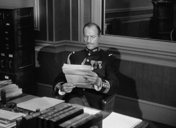 Movie still from “The Life of Emile Zola” (1937), directed by William Dieterle – A man sitting at a table reading a newspaper; Medium shot, Low angle