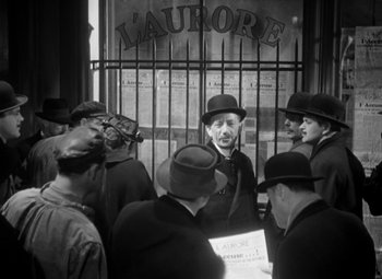 Movie still from “The Life of Emile Zola” (1937), directed by William Dieterle – A group of men standing around a building; Medium shot, Over the shoulder angle