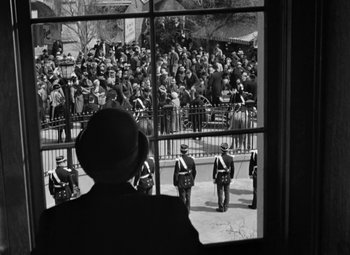 Movie still from “The Life of Emile Zola” (1937), directed by William Dieterle – A group of men in uniform standing in front of a crowd; Wide shot, Over the shoulder angle