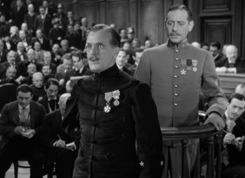 Movie still from “The Life of Emile Zola” (1937), directed by William Dieterle – Two men in military uniforms stand in front of an audience; Medium shot, Over the shoulder angle