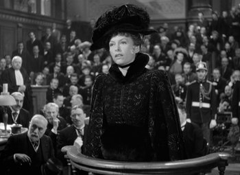Movie still from “The Life of Emile Zola” (1937), directed by William Dieterle – An old photo of a woman in front of an audience; Medium shot, High angle