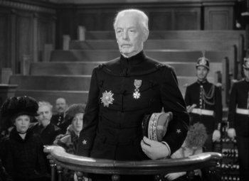 Movie still from “The Life of Emile Zola” (1937), directed by William Dieterle – An older man in a military uniform holding a book; Medium shot, Low angle