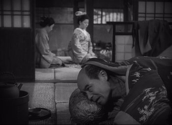 A man laying on the ground in front of two other women