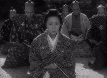 A group of men and a woman sitting on the ground in front of each other