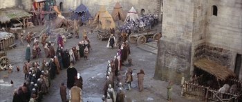 Movie still from “The Lion in Winter” (1968), directed by Anthony Harvey – A crowd of people standing around a building; Extreme Wide shot, High angle