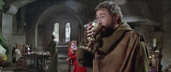 Movie still from “The Lion in Winter” (1968), directed by Anthony Harvey – A man drinking from a cup while standing next to other people; Medium shot, Low angle