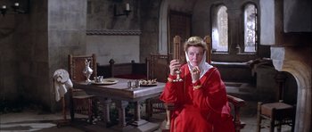 Movie still from “The Lion in Winter” (1968), directed by Anthony Harvey – A woman in a red dress sitting at a dining room table; Medium shot, Low angle