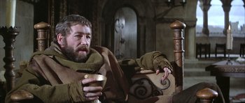 Movie still from “The Lion in Winter” (1968), directed by Anthony Harvey – A man sitting on top of a couch holding a cup; Medium shot, Low angle